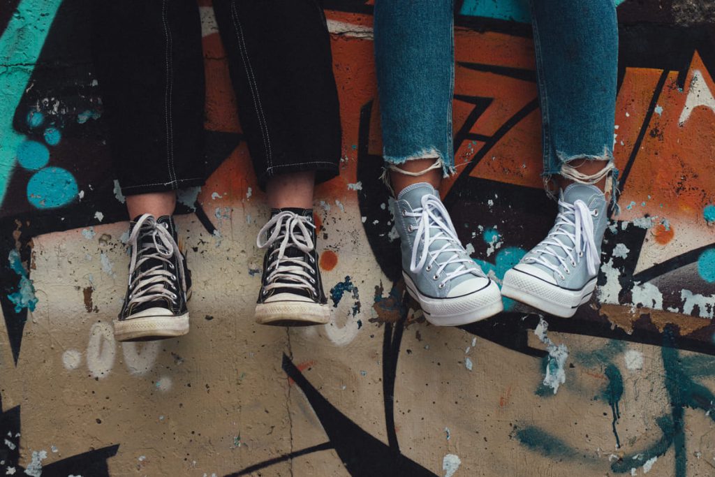 Two friends sitting on a ledge of a skatepark.