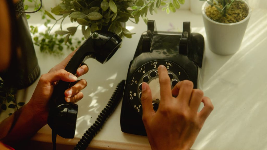 Person using a black rotary phone to make a call.